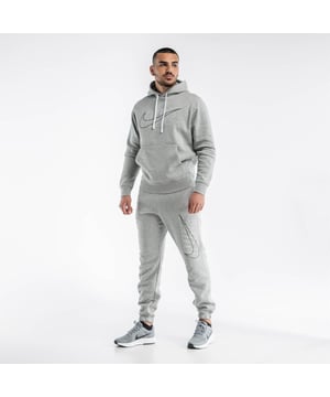 Nike Club trainingspak voor heren in grijs. Hoodie met trekkoord en buidelzak. Overheadontwerp. Nike-logoprint en Swoosh-borduursel op het linkerbeen. Getailleerde versieringen. Bijpassende joggingbroek met elastische taille. Zijzakken, getailleerde manchetten.