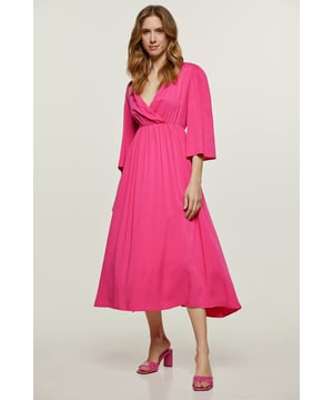 Dieses fuchsiafarbene Sommerkleid in Wickeloptik ist aus gewebtem Stoff gefertigt. Es hat ¾ lange Glockenärmel mit Schlitzen an den Manschetten. Unterhalb der Brust ist es elastisch, wodurch Raffung und eine Empire-Linie entstehen. Das Kleid hat eine lockere Passform und eine Midi-Länge.