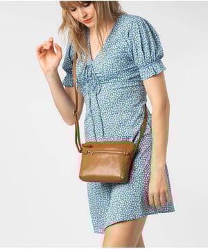 Handcrafted from natural leather, the 'Frida' cross body bag from Conkca London has a beautiful finish. A zip-over top secures a central compartment which is lined with 100% natural cotton and includes two slip pockets - ideal for a phone and keys. On-the-go storage is provided by spacious zipped pockets on the front and back of the bag alongside a slip pocket. This accessory is finished with a slim and adjustable leather strap and adorned with the inimitable Conkca squirrel logo and charm.