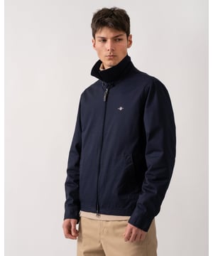 This jacket takes inspiration from GANT's beloved windcheater design, incorporating updated elements for the new season. Crafted from a water-repellent cotton twill shell, it is half-lined to shield against the cold while ensuring breathability. Designed for a regular fit that sits just above the hips, it features a partly elasticated hem for added comfort. Additional details include a front zip closure with a leather extender, slanted side welt pockets with hidden press buttons, two interior jetted pockets, and buttoned cuffs. It is finished with logo embroidery at the chest and a signature branded locker loop at the back. 

Regular fit
Above hip length
Water-repellent (DWR treatment)
Two outer and inner pockets

Shell - 100% Cotton, Upper Back Lining - 100% Cotton, Sleeve Lining - 100% Recycled Polyester 
7006494