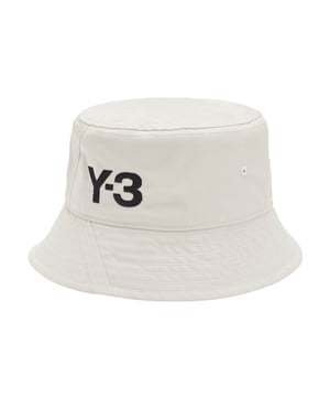 Y-3 klassieke emmerhoed in talk. De bucket hat is synoniem aan street fashion en combineert een gepolijste stijl met casual gemak. Deze versie van Y-3 blijft trouw aan zijn oorsprong, maar voegt opvallende accenten toe. Een monochroom Y-3 logo maakt de look compleet.- Een Y-3 bucket hat.- Oogjes voor ventilatie.- Zweetband aan de binnenkant.- Y-3 logo.- Hoofdmateriaal: 100% polyester (gerecycled).  Voering: 100% nylon (gerecycled).  Handwas koud.- Ref: H62985