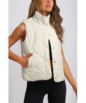 Chaleco acolchado de cuello alto en color beige con botones y bolsillos  
Diseño de cuello alto para mayor aislamiento y una apariencia elegante  
El diseño acolchado ofrece tanto moda como calidez  
Botonadura frontal para un uso fácil y un ajuste seguro  
Ideal para combinar con un suéter y jeans para un look acogedor  
Disponible en varias tallas: S M L XL 2XL  
Material: 100% Poliamida