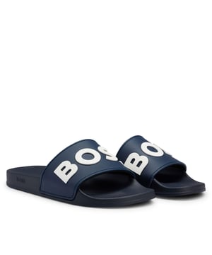 Boss Kirk Sliders voor heren. Nieuw comfortabel bovenwerk verrijkt met iconisch BOSS logo en lycra aan de onderkant voor extra comfort. Nieuwe lichtgewicht PVC-zool. Doorzichtige verpakking en plastic hanger met merkopdruk. Ref: 50488911405.