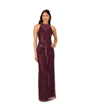 Deco details make this halter gown outshine the competition. This formal dress features a halter bodice, mock neckline, and a column skirt. Draped details at the skirt adds drama to this sleeveless gown. Crafted from mesh knit fabric and embellished with a chic mix of sequins, beading and gems in a design that accentuates the figure. A hidden zipper closure completes this beaded gown. Nude heels and a satin clutch are all this black-tie dress needs to shine all night long.