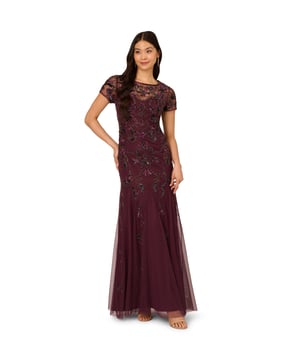 Sparkling beads and sheer details make their mark in this short sleeve beaded gown. This formal dress features a crew neckline with sweetheart illusion neckline, sheer short sleeves, and a mermaid skirt with godet pleats. Lined through the body, this dress has a mesh overlay and is covered in shining sequin and beaded florals. Boasting no waist seam for a comfortable fit, this beaded gown has a sheer back with a centre zip closure. Paired with neutral heels and statement earrings, this beaded dress will fit the bill for formal events and black-tie weddings.