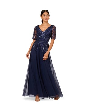 Elegant and opulent, this short sleeve maxi length gown features a mesh overlay embellished in twinkling beads and sequins from the collar to the hips. The back zipper keeps the bodice fitted with the skirt flowing out in an A-line silhouette. A wide V-collar and V-back complement the design and placement of the scrolling beadwork. You will love this elevated sparkling look for your next formal or black-tie occasion.
