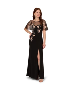 Lean into formal season with this sweetly beaded gown. This formal dress features a fitted bodice with boat neckline, a sheer yoke that gives a sweetheart neckline illusion, sheer flutter sleeves and a mermaid skirt with thigh-high slit. Crafted from crepe fabric through the body, this dress has knit mesh at the bodice and sleeves that is embellished with beautiful sequin beaded florals. A hidden zipper closure at the sheer v-back completes this black-tie dress. Styled with neutral accessories that let the floral beading shine, this flutter short sleeve gown is a romantic look.