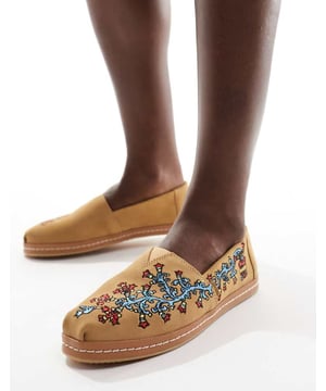 Shoes by Toms Inspired by the traditional alpargata in Argentina Slip-on style Signature TOMS branding Floral embroidery detail Durable rubber outsoleSold By: Asos