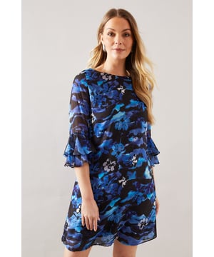 Enchanting floral print shift dress
        Elegant ruffle sleeves for a feminine touch
        Comfortable crew neckline
        Versatile knee-length design
        Keyhole back detail for added allure
    
    Embrace effortless sophistication with this charming floral ruffle sleeve shift dress from Wallis. The eye-catching print creates a captivating look, while the ruffle sleeves add a playful and feminine flair. Perfect for various daytime occasions, this dress can be styled for family gatherings or casual outings. Pair it with flat sandals and a woven tote for a relaxed weekend brunch, or dress it up with wedge espadrilles and statement earrings for a garden party. The versatile knee-length and comfortable fit make it ideal for those who appreciate both style and ease. Layer with a lightweight cardigan for cooler days or wear it on its own to showcase the beautiful print. This Wallis dress is a wardrobe essential that combines comfort and elegance for the modern woman who values both practicality and glamour in her everyday attire.