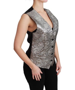 Marke: Dolce & Gabbana  
  Ärmellose Weste  
  Material: 45% Polyester, 43% Seide, 5% Baumwolle, 4% Metallfaser, 3% Elasthan  
  Farbe: Metallisches Silberbrokat  
  Schwarzer Seidenrücken  
  Verstellbarer Rückengurt  
  Hergestellt in Italien