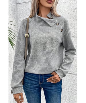 Sudadera gris de cuello alto  
Detalles de botones asimétricos en el frente  
Tejido texturizado con una sensación suave  
Versátil para ocasiones informales y formales  
Material: 95% poliéster 5% elastano
