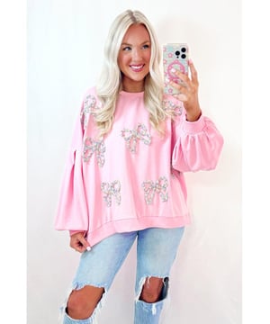 Sudadera de pullover a la moda para uso casual  
Color rosa claro con lazos bordados para un toque femenino  
Mangas farol y corte oversized para un look voluminoso  
Se puede combinar con jeans o pantalones cortos de mezclilla  
Ideal para el uso diario  
Material: 65% Poliéster 35% Algodón