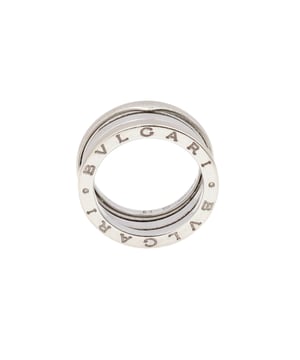 VINTAGE, RRP AS NEW
B.Zero1 Bulgari Ring: Pre-owned B.Zero1 Bulgari ring in 18K white gold. Wide band measuring approximately 9mm in width decorated with a cylindrical spiral motif. The Bulgari signature appears on both sides of the motif. The ring is presented with its original box. Condition: Very good condition. This pre-owned ring has been refurbished and cleaned by a professional jeweler then carefully re-packaged in its original packaging. Details: - 18K white gold. - Band width: 9mm. - Ring size: 52. - Weight: - Packaging and Certificates: - Original taupe Bulgari box. (Condition: good) - Certificate of authenticity issued by our partner expert.