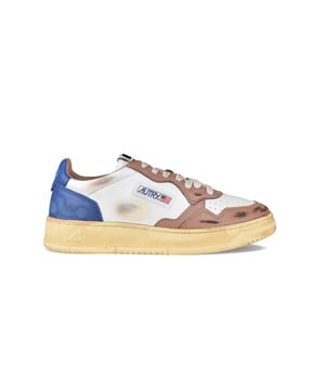 Sneakers bajas Autry super vintage.En piel azul, blanca y marrón. Efecto desgastado.Parche del logotipo en el exterior. Contrafuerte de cuero azul con logotipo en relieve.Lengüeta con parche del logotipo.Suela de caucho con efecto vintage amarillento. Cierre con cordones planos. Puntera redonda perforada.100% piel.