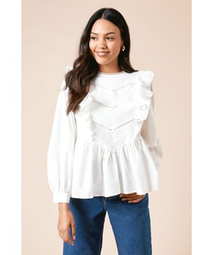 Charming blouson sleeves with elasticated cuffs for a feminine silhouette
        Delicate embroidered trim along the crew neckline adding subtle detail
        Elegant ruffle detailing across the bodice for a textured finish
        Flattering peplum-style waist creating a graceful shape
        Keyhole button fastening at the back for a secure yet stylish fit
    
    This Dorothy Perkins top combines classic charm with contemporary styling, perfect for the woman who appreciates thoughtful details. The cotton fabric offers breathable comfort whilst the ruffle detailing and blouson sleeves create a romantic aesthetic that's both on-trend and timeless. Style with your favourite denim jeans and trainers for casual weekend brunches, or dress up with tailored trousers and ballet flats for family gatherings. The versatile crew neckline works beautifully with delicate jewellery for added sophistication. This top transitions effortlessly from day to evening - simply swap your tote bag for a clutch and add statement earrings. The relaxed yet put-together look makes it an ideal choice for baby showers or informal garden parties where comfort and style are equally important.