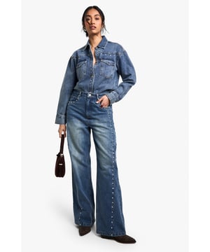 Eye-catching stud detailing along the outer seams
        Wide-leg silhouette for a trendy, relaxed fit
        High-waisted design for a flattering shape
        Classic five-pocket styling
        Versatile medium wash denim
    
    Make a statement with these attention-grabbing jeans from Boohoo. The striking stud detailing along the outer seams adds a touch of edgy glamour to the classic denim design. The wide-leg silhouette offers both comfort and style, perfect for the fashion-forward woman who values both trends and ease. Pair these jeans with a cropped denim jacket for a coordinated double denim look, or dress them up with a silky blouse and heels for a night out. The high-waisted cut is ideal for tucking in tops or wearing with shorter lengths. These jeans are a versatile addition to any wardrobe, suitable for casual outings, family gatherings, or relaxed social events. The medium wash denim complements a variety of tops and accessories, making these jeans a go-to choice for creating numerous stylish ensembles.