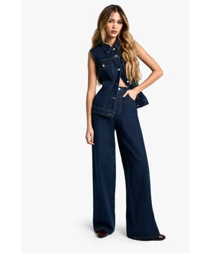 Sleeveless denim jumpsuit with wide-leg silhouette
        Button-up front with classic collar
        Functional chest pockets for added utility
        Wide belt loops to accommodate various belt styles
        Relaxed fit through hips and legs for maximum comfort
    
    Make a bold statement with this eye-catching wide-leg denim jumpsuit. Perfect for the fashion-forward woman who loves to stand out, this versatile piece can be dressed up or down for various casual occasions. Style it with trainers and a cropped cardigan for a laid-back weekend look, or pair it with heeled boots and statement earrings for a night out with friends. The sleeveless design makes it ideal for layering, allowing you to customise your look according to the weather or your mood. Whether you're heading to a family gathering or a casual brunch date, this jumpsuit offers both comfort and style. The wide-leg cut elongates your silhouette, while the button-up front allows for easy wear. Embrace the retro-inspired trend and make this jumpsuit your go-to piece for effortless, head-turning style.