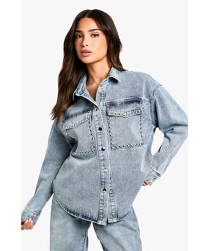 Oversized denim shirt featuring eye-catching stud detailing along the pockets
        Relaxed drop shoulder design for that effortlessly cool aesthetic
        Front button fastening with classic collar for versatile styling options
        Spacious chest pockets with distinctive stud embellishment
        Specially designed for petite frames whilst maintaining the trendy oversized silhouette
    
    This statement denim shirt combines casual comfort with edgy detailing, perfect for the fashion-forward woman who loves to make an impression. The oversized fit creates a relaxed silhouette that works brilliantly when paired with matching denim for a coordinated ensemble, as shown by our model. Layer over a simple vest top and team with wide-leg trousers for a contemporary daytime look, or half-tuck into high-waisted jeans for a more defined shape. The stud detailing adds a touch of attitude to casual gatherings and weekend brunches. For cooler days, style under an oversized blazer with trainers for an on-trend casual outfit, or dress up with ankle boots and statement jewellery for evening drinks. This versatile Boohoo piece transitions effortlessly from day to night whilst maintaining that coveted laid-back vibe.