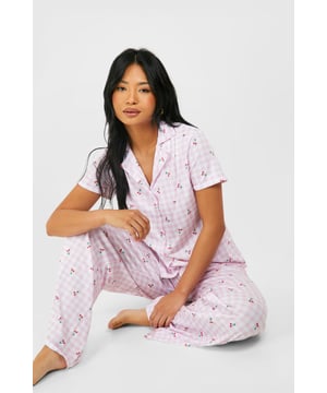 Charming gingham pattern with adorable cherry print
        Short-sleeved top with classic collar and button-down front
        Relaxed fit trousers for ultimate comfort
        Soft knitted fabric for a cosy feel
        Versatile two-piece set perfect for lounging or sleeping
    
    Drift off to dreamland in style with this delightful petite pyjama set. The charming gingham pattern, adorned with a playful cherry print, adds a touch of whimsy to your nighttime routine. The short-sleeved top features a classic collar and button-down front, allowing for easy wear and a put-together look even as you unwind. Paired with relaxed-fit trousers, this set ensures unrestricted movement and comfort throughout the night. The soft knitted fabric envelops you in cosiness, making it ideal for those lazy weekend mornings or evening Netflix marathons. Whether you're catching some shut-eye or enjoying a leisurely breakfast in bed, this versatile pyjama set has got you covered. For a complete loungewear look, team with fluffy slippers and a plush dressing gown for the ultimate in comfort and style.