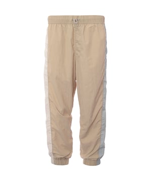 Main: 100% Polyamide. Tommy Jeans nylon blend joggers in beige are the epitome of comfort meets style. With their snug cuffed legs, they offer a modern silhouette that's perfect for a relaxed weekend or a casual outing. The subtle thick stripe down the side adds a touch of sporty elegance, making them a versatile addition to any wardrobe. Whether you're lounging at home or stepping out for a coffee, these joggers blend functionality with a trendy aesthetic.