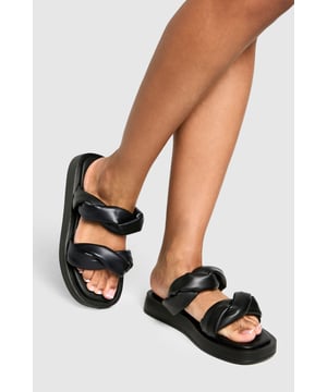 Wide fit design for enhanced comfort and easy wear
        Distinctive twisted strap detail adding contemporary flair
        Flat sole with height between 0-2cm for all-day wearability
        Smooth PU construction offering a sleek, polished finish
        Cushioned footbed providing essential support for extended wear
    
    These statement slides redefine casual footwear with their eye-catching twisted strap detail. The wide fit design ensures maximum comfort whilst the flat sole makes them perfect for those busy days when style can't compromise practicality. Pair with cropped wide-leg trousers and an oversized linen shirt for a sophisticated daytime look, or team with a flowing maxi dress for relaxed weekend brunches. The versatile design transitions effortlessly from poolside lounging to casual city strolls. Their minimalist aesthetic works brilliantly with both neutral tones and vibrant outfits, making them a wardrobe essential for the fashion-forward woman who values both comfort and contemporary style. Ideal for family gatherings, festival outings, or holiday explorations when you need footwear that's as reliable as it is stylish.