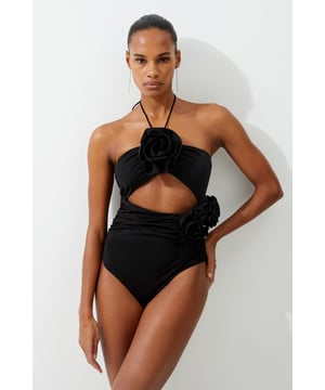 Welcome the sun with a swimming costume that will turn heads, featuring a three dimensional corsage accent on the bust and hip, and a statement cut out design in the front and back. Style this piece with strappy sandals and a beach cover up for a holiday look that can be reworn time and time again. Rosette Cut Out Detail Swimsuit Flattering Halter Neckline Unique, Three Dimensional Flower Accent Statement Cut Out Design Tie and Clasp Fastening in Back