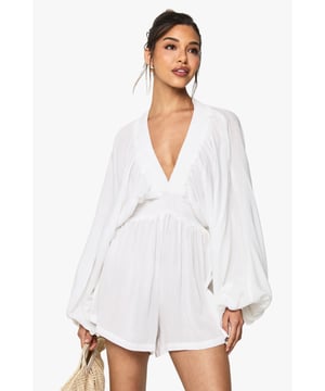 Lightweight cheesecloth playsuit with plunge neckline for a striking silhouette
        Dramatic long sleeves with voluminous design for added flair
        Elasticated waistband creates a flattering, defined shape
        Relaxed fit shorts provide comfort and ease of movement
        Back keyhole detail with button fastening adds a subtle finishing touch
    
    This effortlessly chic playsuit from Boohoo combines comfort with head-turning style. The lightweight cheesecloth fabric drapes beautifully across the body, while the plunging neckline creates a bold focal point that's perfect for warm-weather socialising. The billowing long sleeves add drama to this casual piece, balancing the shorter length of the playsuit. Style with strappy sandals and a woven clutch as seen on our model for daytime gatherings, or dress up with metallic accessories and statement earrings for sunset drinks. The versatile design works brilliantly for family barbecues, beach outings or casual coffee dates. For cooler evenings, layer with a denim jacket and switch to ankle boots for an outfit that transitions seamlessly from day to night. Machine washable and easy to care for, this playsuit will quickly become your go-to for effortless summer style.