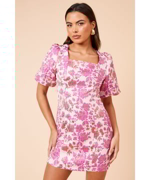 Elegant jacquard fabric with a striking floral pattern that catches the light beautifully
        Sophisticated square neckline that frames the dcolletage perfectly
        Flattering mini length that showcases your legs whilst maintaining elegance
        Charming puff sleeves with subtle volume for a contemporary silhouette
        Fully lined for comfort and a smooth fit against the skin
    
    This DP Luxe floral jacquard mini dress combines timeless femininity with modern design elements. The textured jacquard fabric creates visual interest whilst the square neckline offers a refined touch that works beautifully for special occasions. Style with strappy heeled sandals as shown for garden parties or summer weddings, or dress it down with white trainers and a denim jacket for sophisticated brunches with friends. The mini length and structured silhouette create a flattering shape that's both youthful and appropriate for the thirty-something woman who appreciates fashion-forward pieces without revealing too much. Perfect for baby showers, engagement celebrations or race day events when paired with a fascinator and clutch bag. The metallic thread woven throughout adds a subtle shimmer that transitions effortlessly from day to evening occasions.