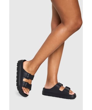 Wide fit design for enhanced comfort
        Double strap with adjustable buckle fastening
        Chunky cleated sole for added grip
        Flat heel measuring between 0-2cm
        Versatile slip-on style for easy wear
    
    Step into comfort and style with these trendy wide fit slides from Boohoo. Perfect for the fashion-forward woman who values both aesthetics and practicality, these sandals are a must-have for your casual wardrobe. The double strap design with adjustable buckles allows for a customised fit, while the chunky cleated sole adds a contemporary edge and ensures stability. Ideal for various casual occasions, from relaxed family gatherings to laid-back outings with friends, these slides effortlessly blend comfort with urban chic. Pair them with cropped jeans and an oversized tee for a cool, off-duty look, or style them with a flowing maxi dress for a boho-inspired ensemble. The versatility of these slides makes them a go-to choice for your everyday adventures, offering both comfort and style in equal measure.