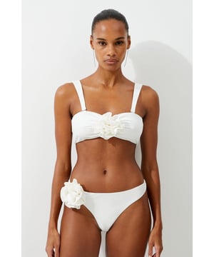 Welcome the sun with a bikini that will turn heads, the top of which features a three dimensional corsage accent at the cleavage, and a comfortable bandeau style, with optional, wide shoulder straps. Style this piece with the matching bikini bottoms, strappy sandals, and a beach cover up for a holiday look that can be reworn time and time again. Rosette Detail Bandeau Bikini Top Comfortable Bandeau Style Unique, Three Dimensional Flower Accent at Cleavage Optional, Wide Shoulder Straps Clasp Fastening in Back Matching Bikini Bottoms Sold Separately