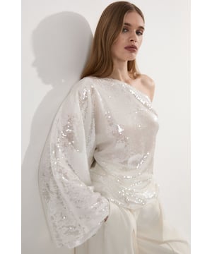 Make a statement at your next event with this eye-catching Liquid Shine One Shoulder Woven Sequin Blouse from Karen Millen. The asymmetrical neckline creates a bold silhouette, while the all-over sequin embellishment ensures you'll shimmer and shine all night long. The loose fit offers comfort without compromising on style, and the dramatic bell sleeve adds a touch of theatrical flair. Perfect for formal events, this blouse can be styled with tailored trousers and stilettos for a sophisticated evening look. Alternatively, pair it with a sleek pencil skirt and strappy heels for a head-turning ensemble at weddings or cocktail parties. The versatility of this piece allows for endless styling options, making it a valuable addition to your occasion wear wardrobe.  Striking one-shoulder design for a bold, asymmetrical look All-over sequin embellishment creates a dazzling, liquid-like shine Loose fit for comfortable and effortless wear Dramatic bell sleeve adds a touch of glamour Versatile blouse suitable for various formal occasions
