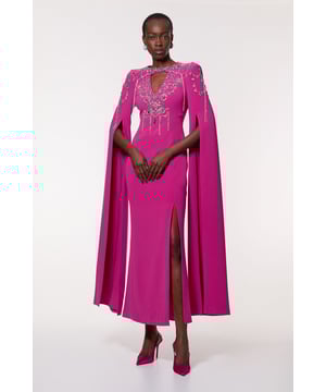 Feel like the centre of attention in our maxi dress, which features a fit that hugs the curves, statement sparkling embellishments, and a unique cape feature that brings the drama. Styles well with strappy heels for a statement occasion look, perfect for prom night, as a wedding guest dress, or for formal occasions. Crystal Embellished Cady Woven Cape Maxi Dress Sparkling Crystal Detailing Statement Cape Sleeve Feature Figure Skimming Fit Striking Thigh High Leg Split Cut Out Accent at Bust and in Back Hook and Zip Back Fastening