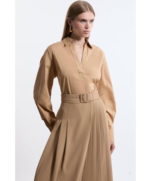 Feel elevated in our classic shirt, featuring a relaxed fit, and a V neckline. This piece can be easily paired with anything from tailored trousers to denim jeans for looks that go from office days to dinner dates. Tailored Cotton V Neck Shirt Flattering Relaxed Fit Classic, Collared Neckline Deep V Neckline Matching Skirt Sold Separately