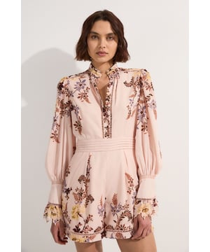 This Karen Millen playsuit is a captivating choice for your next special occasion. The intricate floral border print creates a mesmerising visual effect, while the airy voile fabric ensures comfort throughout your event. Style this versatile piece with strappy metallic heels and statement earrings for a wedding or garden party. For a more relaxed look, pair it with wedge sandals and a woven clutch for alfresco dining. The high neck and long sleeves make it suitable for cooler evening events, simply layer with a cropped blazer. This playsuit effortlessly transitions from day to night, making it a valuable addition to your occasion wear wardrobe. Its unique blend of femininity and sophistication will ensure you stand out at any formal gathering.  Enchanting floral border print adorns the lightweight voile fabric Elegant high neck design with delicate ladder lace trim Voluminous long sleeves with gathered cuffs for a romantic silhouette Fitted waistband accentuates the figure Playful short length with a subtle ruffle hem