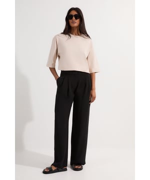 These Karen Millen tailored trousers present the perfect balance of comfort and sophistication for your workwear collection. The soft woven fabric offers a fluid drape while maintaining structure throughout the day. Style them as shown with a simple cropped top for a contemporary office ensemble, or pair with a crisp button-down shirt and blazer for more formal settings. The versatile straight leg cut works beautifully with both flat shoes and heels, making these trousers ideal for transitioning from day to evening events. Their timeless design ensures they'll become a cornerstone of your professional wardrobe, easily coordinating with existing pieces for countless outfit combinations. Perfect for presentations, important meetings, or any occasion where you need to project polished confidence.  Soft tailored straight leg trousers with elegant front pleats for added dimension Flattering high-rise waistband with belt loops for versatile styling options Practical side pockets seamlessly integrated into the design Clean straight leg silhouette that creates a refined, elongated look Full-length design with a sophisticated drape that falls elegantly to the floor