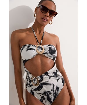 Make a statement in this head-turning swimsuit from Karen Millen. The bold palm print exudes exotic charm, while the strategically placed cut-out and gold-tone ring add a touch of glamour. The halterneck design offers support and adjustability, perfect for lounging by the pool. Style it with oversized sunglasses and a wide-brimmed hat for the ultimate beach look. For a stylish cover-up, pair with a sheer kaftan and strappy sandals. This versatile piece transitions effortlessly from daytime beach adventures to sunset cocktails at the resort bar. Whether you're jetting off to a tropical paradise or enjoying a staycation, this swimsuit will ensure you look and feel fabulous.  Striking palm print design for a tropical vibe Halterneck style with eye-catching cut-out detail Decorative gold-tone ring embellishment at the centre High-cut leg for an elongating effect Slinky fabric for a smooth, figure-hugging fit