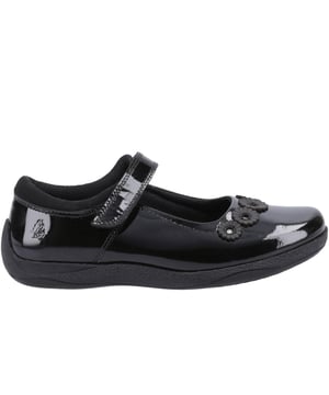 Zapatos negros de charol Hush Puppies Christina para niña, fabricados con sintético y suela de goma. Incluyen: cierre de velcro, suela de goma, plantilla acolchada, detalle de flor y parte superior de charol.