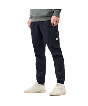 Heren Weekend Offender Hoshino Cargo Pant in navy.- Elastische tailleband met verstelbaar koord.- Achter paspelzak met verborgen drukknoopsluiting.- Meerdere cargozakken.- Ritstrekkers met WO merknaam.- Afneembare WO badge op beenzak.- Comfort rib manchetten.- Verstevigde stiksels voor extra duurzaamheid.- Normale pasvorm met verstelbare kenmerken voor een op maat gemaakte comfortabele pasvorm.- Ref: WPAW2406NAV
