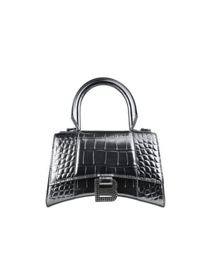 Bolso de mano Balenciaga Hourglass plateado.Piel de becerro grabada en cocodrilo.Placa con logotipo B de la firma en strass.Detalles metálicos plateados.Solapa superior con cierre de botón a presión.Asa redondeada.Bandolera extraíble y ajustable. Medidas: 19 cm x 12 cm x 8 cm.Talla pequeña.Made in Italy.