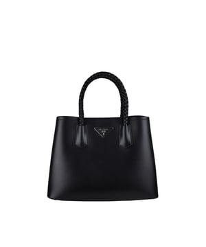 Bolso Double de Prada en suave piel negra.Icónico logotipo triangular plateado en la parte delantera del bolso.Doble asa de piel trenzada.Bandolera extraíble y ajustable.Detalles metálicos plateados.Cierre de botón de presión lateral.Dimensiones: 34 x 25 x 15 cm.100% piel.Made in Italy.