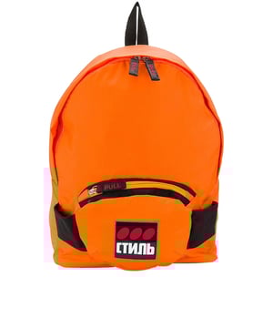 Mochila Heron Preston de tejido naranja.Gran bolsillo con cremallera.Pequeño bolsillo con cremallera en la parte delantera.Pequeña asa negra en la parte superior.Tirantes negros ajustables.Parche con inscripción  Стиль  en el bolsillo delantero.Dimensiones : 33x44x14cm.Made in Italy.