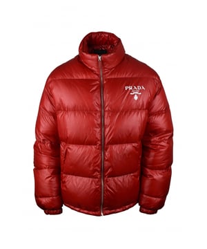 Chaqueta acolchada roja en re-nylon Prada.Logo blanco impreso en el pecho.Cuello alto.Cierre principal con cremallera.Bolsillos laterales con cremallera.