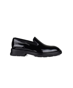 Mocasines Alexander McQueen Slip-on Tread en charol negro.Detalles en los contornos.Puntera redondeada.Logotipo de la marca en relieve en la parte posterior de la suela.Suela de goma negra. Made in Italy.