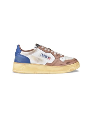 Sneakers bajas Autry Super vintage en piel blanca/marrón y azul oscuro.Inserciones de piel y efecto desgastado. Parche con logotipo en el exterior.Talonera de piel azul con logotipo en relieve.Lengüeta con parche del logotipo.Suela de goma efecto vintage en contraste. Cierre con cordones blancos.Puntera redonda perforada.100% piel.