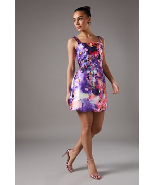 Elegant square neckline with wide shoulder straps for a sophisticated silhouette
        Striking watercolour floral print that creates a captivating visual effect
        Flattering mini length that showcases your legs beautifully
        Distinctive cut-out detail at the back adds an unexpected contemporary twist
        Structured twill fabric that maintains its shape throughout your event
    
    This enchanting mini dress from Coast combines artistic flair with occasion-worthy elegance. The square neckline frames your dcolletage perfectly, whilst the structured twill fabric ensures a flattering fit that maintains its shape as you move. The eye-catching back cut-out detail introduces a modern element to this otherwise classic silhouette. Style with strappy heels and delicate jewellery for summer weddings or race day events-the model demonstrates how minimal accessories allow the dress to command attention. For cooler occasions, layer with a tailored blazer and clutch bag for a refined ensemble that transitions seamlessly from day to evening. This versatile piece works equally well for garden parties, graduation ceremonies or sophisticated cocktail events where you wish to make a memorable impression.