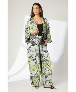 Striking leaf print kimono in luxurious satin fabric
        Loose-fitting silhouette with open front design
        Elegant wide sleeves for dramatic drape
        Floor-length style measuring 128cm from shoulder to hem
        Versatile layering piece perfect for seasonal transitions
    
    This statement Principles kimono transforms any casual ensemble into something extraordinary. The flowing satin fabric creates beautiful movement as you walk, whilst the bold leaf print adds artistic flair to your wardrobe. Layer over a simple black vest top and wide-leg trousers as styled on our model for an effortlessly chic daytime look. The generous proportions make this piece ideal for garden parties, brunches with friends or relaxed family gatherings. Pair with flat sandals and statement earrings for a sophisticated summer ensemble, or throw over jeans and a simple tee to instantly refresh your everyday style. The kimono's dramatic silhouette works beautifully for holiday evenings or special lunch occasions when you want to convey relaxed confidence with minimal effort.