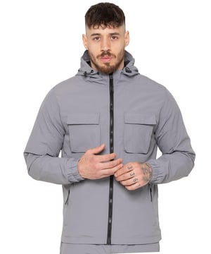 The Enzo Milano Men’s Lightweight Cargo Jacket is a sleek, functional outer layer made from water-repellent crushed poly fabric with a breathable mesh lining for all-day comfort. Designed in a regular fit, it features a full zip front, high neck, and adjustable drawcord hood for versatile coverage. With two Velcro chest pockets, two zippered side pockets, elasticated cuffs, and an adjustable drawcord hem, it offers both style and practicality—perfect for layering in changing weather.