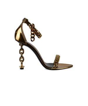 Sandalias Tom Ford en piel metalizada dorada.Estilo de tiras. Cadena dorada en la tira delantera del tobillo.Hebilla en el tobillo.Acabados dorados.Tacón de cadena dorada.Puntera abierta en punta.Altura del tacón 10 cm.Made in Italy.