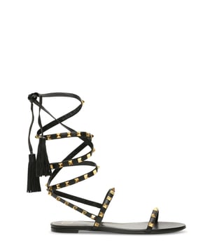Sandalias Valentino Garavani en piel color negro.Tirantes de piel con tachuelas doradas y borlas de piel.Suela con tacón plano.Made in Italy.