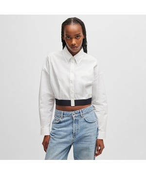 Dames HUGO Evesia Relaxed-fit blouse met contrasterende merkband in de taille in wit.Een volumineuze blouse in een moderne korte lengte van HUGO. Uitgevoerd in zachte popeline en voorzien van een gestapeld logo op de contrasterende elastische tailleband. Dit product is gedeeltelijk gemaakt van organisch katoen.- Relaxed fit- Puntkraag- Lange mouwen- Knoopmanchetten- Korte lengte- Plooidetail aan de achterkant voor extra volume- Contrasterende elastische tailleband met ton-sur-ton gestapeld logo- Hoofdmateriaal: 100% katoen.  Machinewasbaar.- Ref: 50518040-100